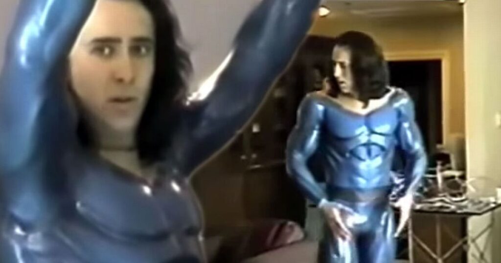 Nicolas Cage sul set di Superman Lives con tuta blu capelli lunghi mostrando muscoli